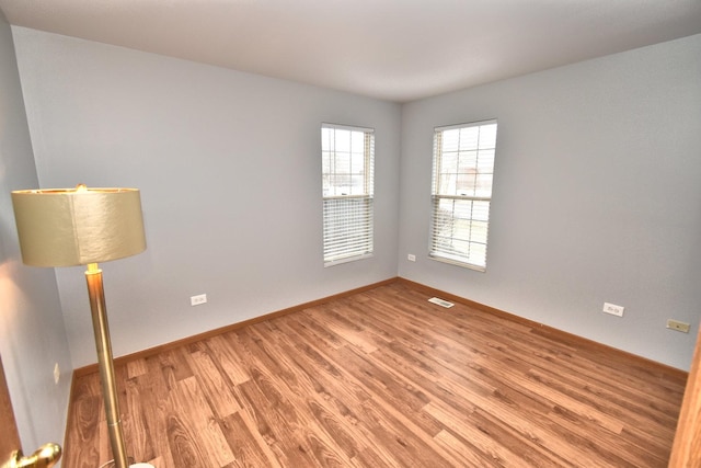 unfurnished room with baseboards, visible vents, and light wood-style floors