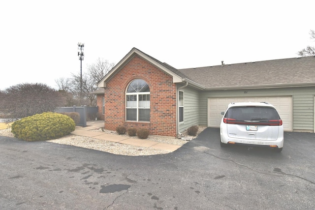 view of front facade with a garage, brick siding, driveway, and a shingled roof