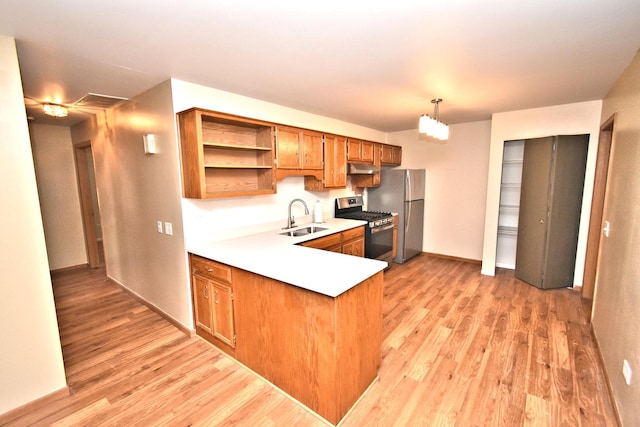 kitchen featuring light wood-style floors, appliances with stainless steel finishes, brown cabinets, and a sink