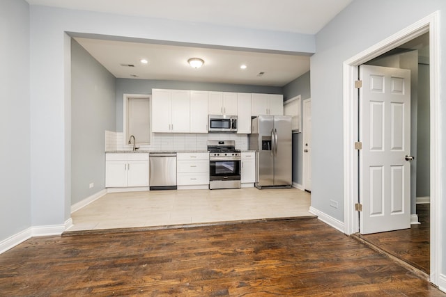 kitchen featuring stainless steel appliances, white cabinets, a sink, and tasteful backsplash