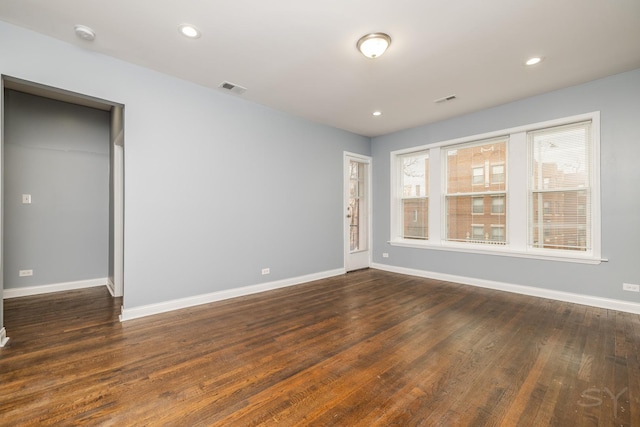 unfurnished room with dark wood-style floors, baseboards, and visible vents