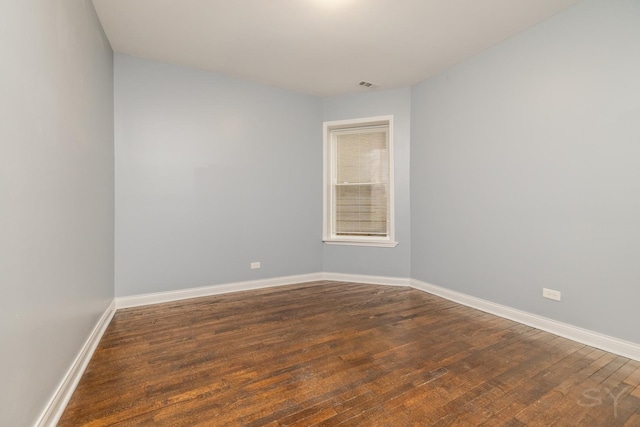 unfurnished room with visible vents, baseboards, and dark wood-type flooring