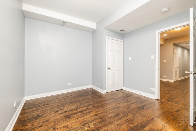 spare room featuring dark wood-style floors, visible vents, and baseboards