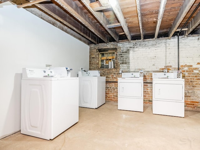 laundry area with washer and dryer and brick wall