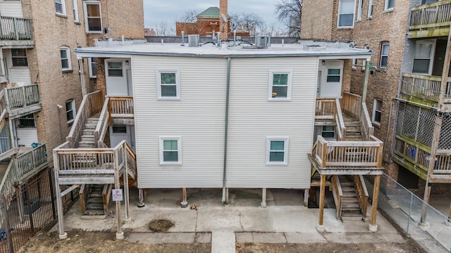 rear view of house featuring fence and stairway