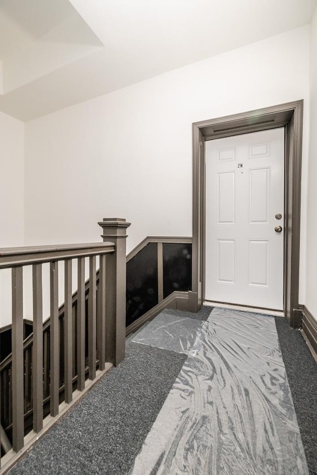 hallway with carpet flooring and an upstairs landing