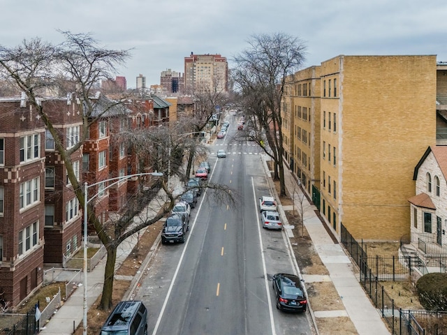 view of road with street lights, curbs, sidewalks, and a city view