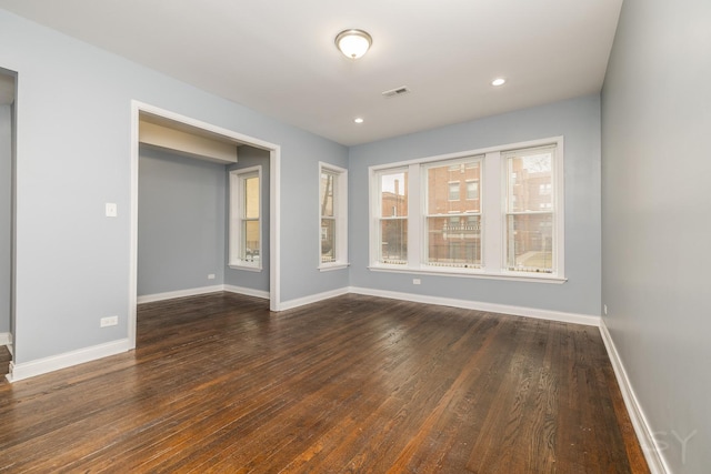 empty room with baseboards, visible vents, dark wood finished floors, and recessed lighting