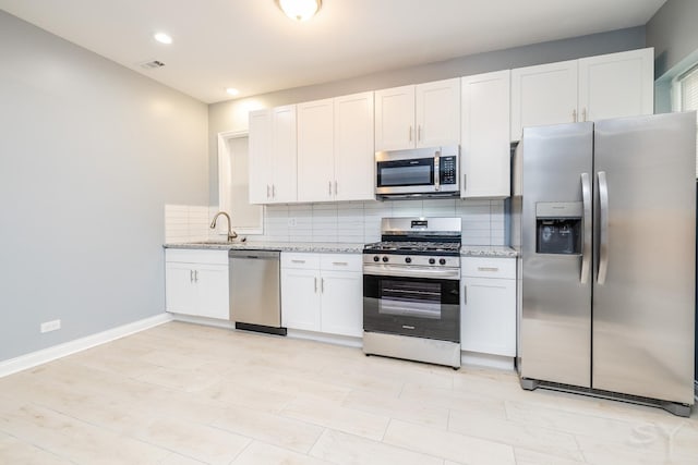 kitchen with stainless steel appliances, visible vents, light stone counters, and decorative backsplash