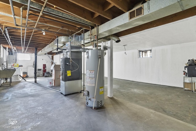 basement featuring gas water heater, visible vents, electric panel, and a healthy amount of sunlight