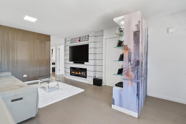 living area featuring baseboards, wood finished floors, and a glass covered fireplace