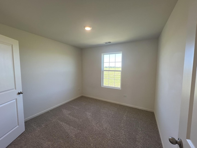 empty room with baseboards, visible vents, and dark carpet