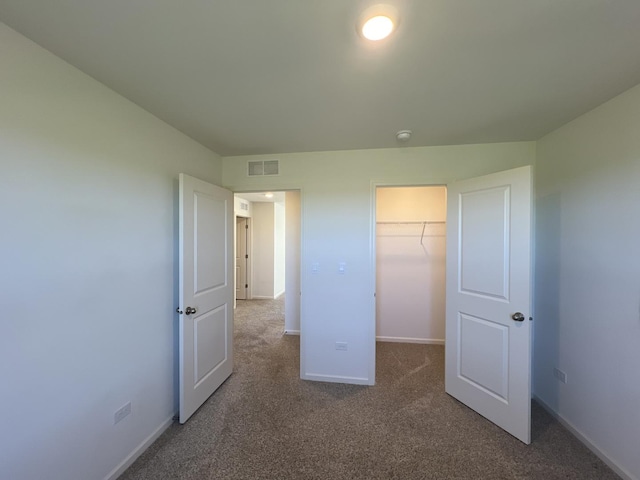 unfurnished bedroom with baseboards, visible vents, carpet floors, a spacious closet, and a closet