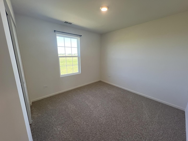 spare room with carpet flooring, visible vents, and baseboards