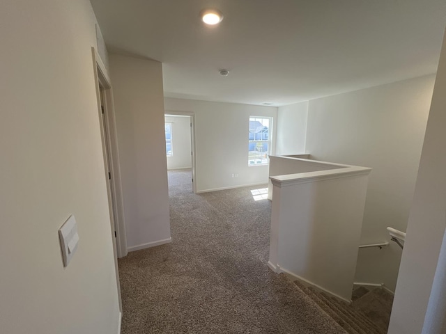 hall featuring baseboards, an upstairs landing, and carpet flooring