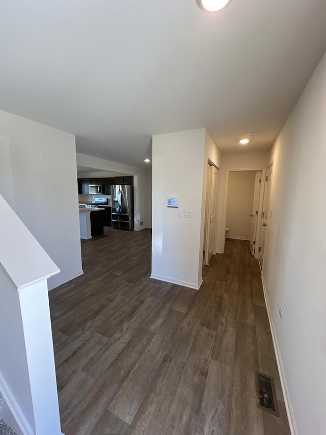 hallway with dark wood finished floors, baseboards, and visible vents