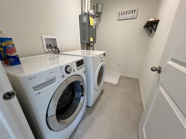 clothes washing area featuring laundry area, baseboards, water heater, and washer and clothes dryer