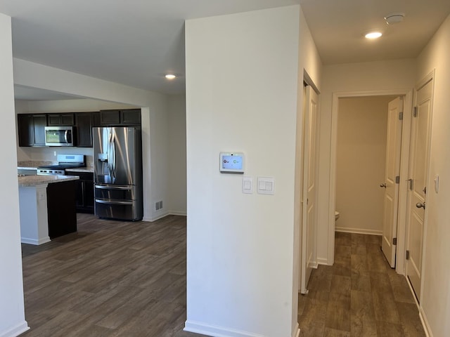 hall with visible vents, baseboards, and dark wood finished floors