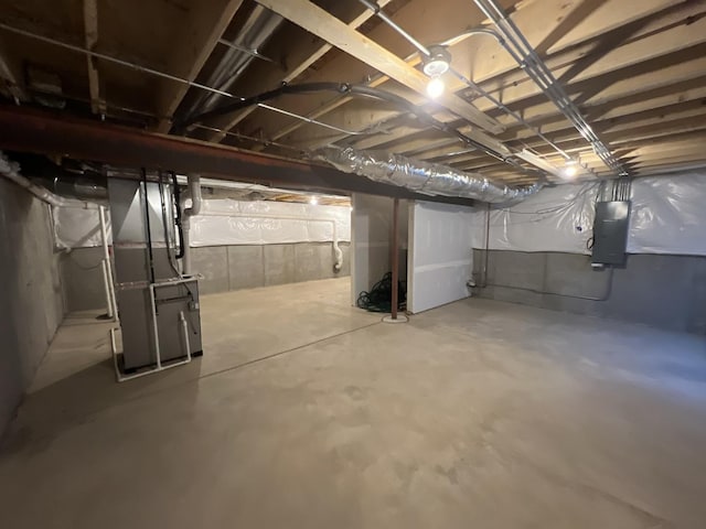 unfinished below grade area featuring electric panel and heating unit