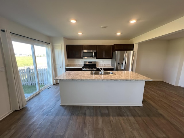 kitchen featuring dark wood-type flooring, dark brown cabinetry, a center island with sink, stainless steel appliances, and a sink