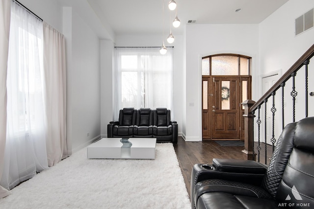 living area with stairs, wood finished floors, visible vents, and baseboards