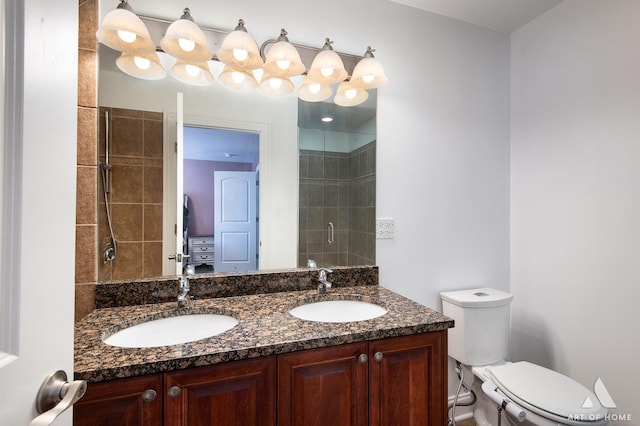 bathroom featuring tiled shower, a sink, toilet, and double vanity