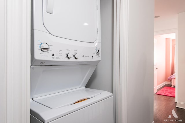 laundry area featuring laundry area, baseboards, stacked washing maching and dryer, and wood finished floors