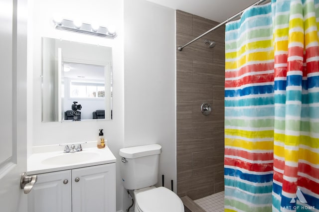 bathroom with toilet, a tile shower, and vanity