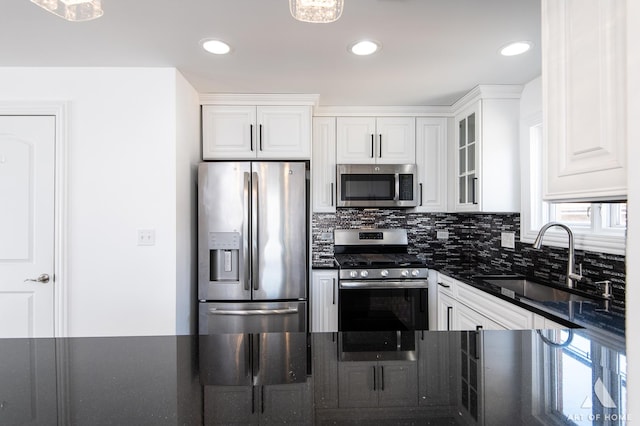 kitchen featuring stainless steel appliances, decorative backsplash, glass insert cabinets, white cabinets, and a sink