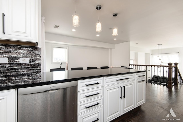 kitchen featuring visible vents, dark countertops, stainless steel dishwasher, white cabinetry, and backsplash