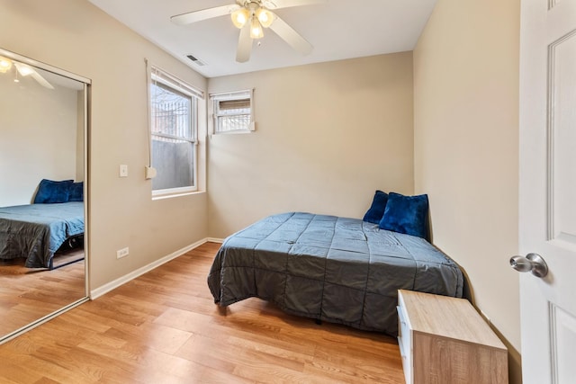 bedroom featuring ceiling fan, light wood-style flooring, visible vents, baseboards, and a closet