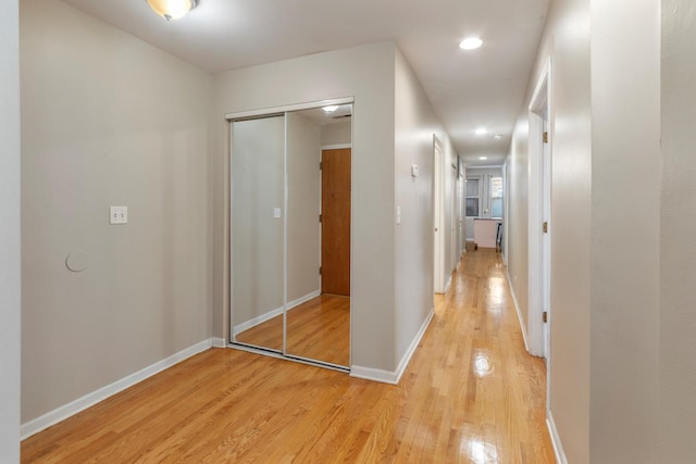 hall featuring light wood-style floors, baseboards, and recessed lighting