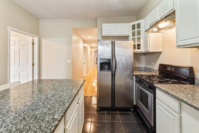 kitchen with stainless steel appliances, glass insert cabinets, white cabinets, dark stone countertops, and under cabinet range hood