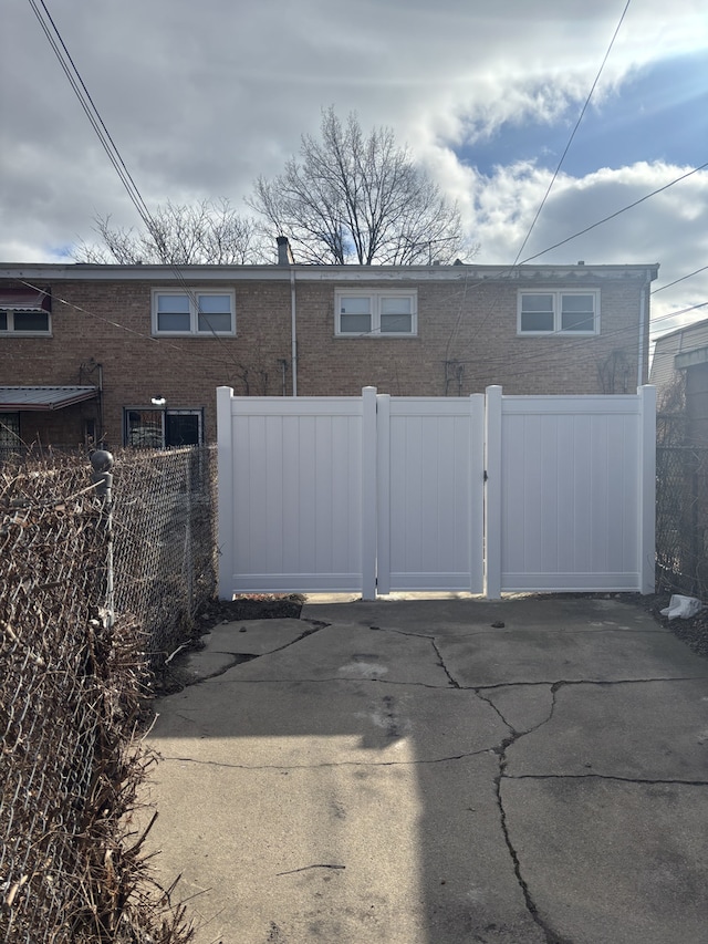 exterior space with brick siding, fence, and a gate