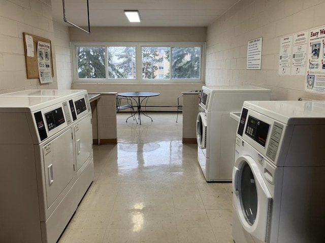 common laundry area with concrete block wall, a baseboard heating unit, and separate washer and dryer