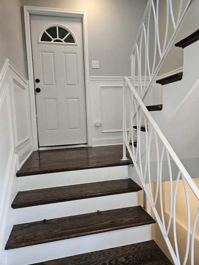 staircase with wainscoting, wood finished floors, and a decorative wall