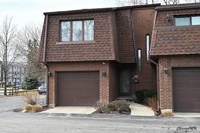 view of front of property featuring mansard roof, an attached garage, brick siding, and a shingled roof