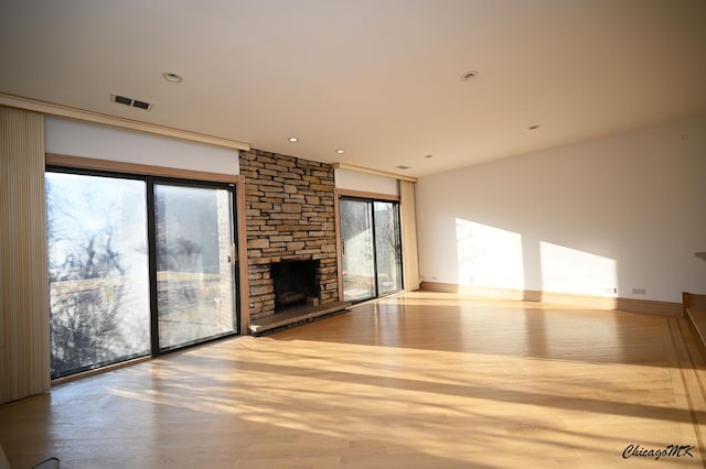 unfurnished living room featuring recessed lighting, visible vents, wood finished floors, and a stone fireplace