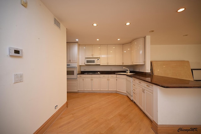 kitchen with dark countertops, recessed lighting, visible vents, light wood-style flooring, and white appliances