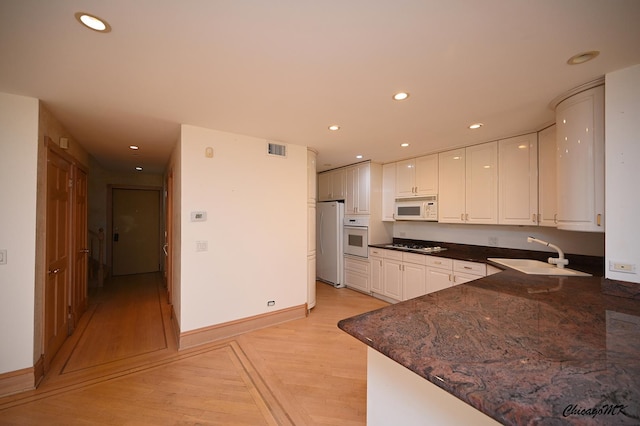 kitchen featuring light wood-style flooring, recessed lighting, white appliances, a sink, and visible vents