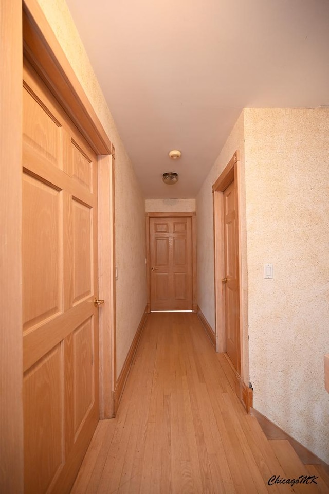 hallway featuring light wood-type flooring and baseboards