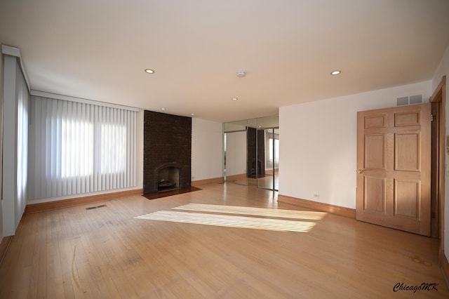 unfurnished living room featuring recessed lighting, a brick fireplace, visible vents, and light wood finished floors