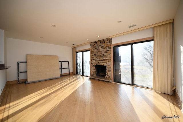 unfurnished living room featuring visible vents, a fireplace, light wood-style flooring, and baseboards