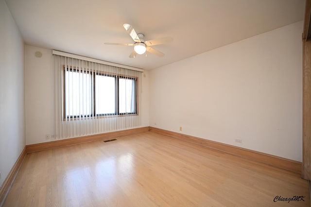 spare room with light wood finished floors, baseboards, and visible vents