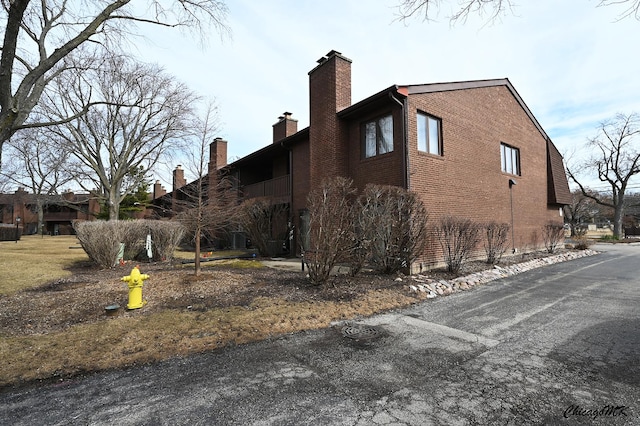 view of property exterior with brick siding and a chimney