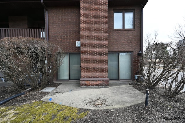 rear view of property featuring brick siding and a patio