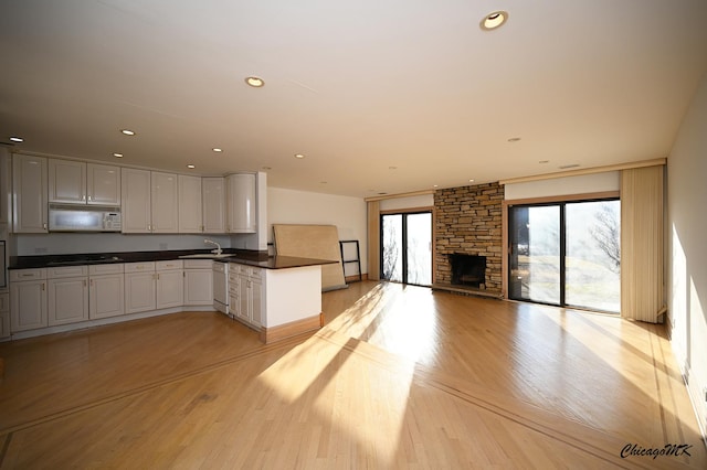 kitchen featuring recessed lighting, a peninsula, white appliances, light wood-style floors, and dark countertops