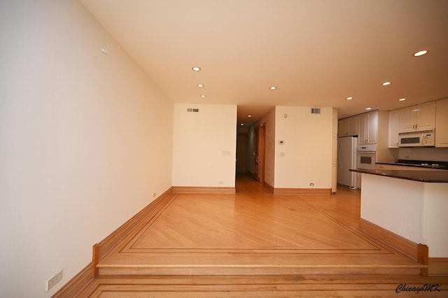 interior space with dark countertops, recessed lighting, light wood-style floors, white cabinetry, and white appliances