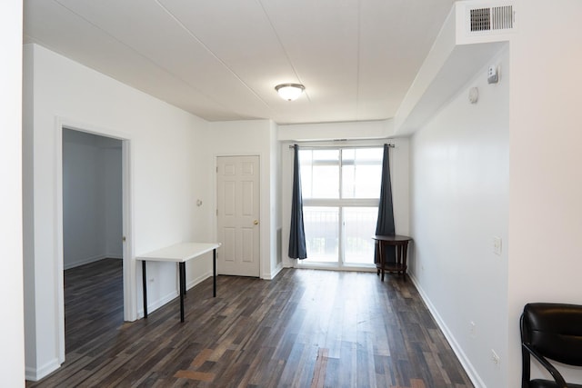 spare room with baseboards, visible vents, and dark wood-style flooring