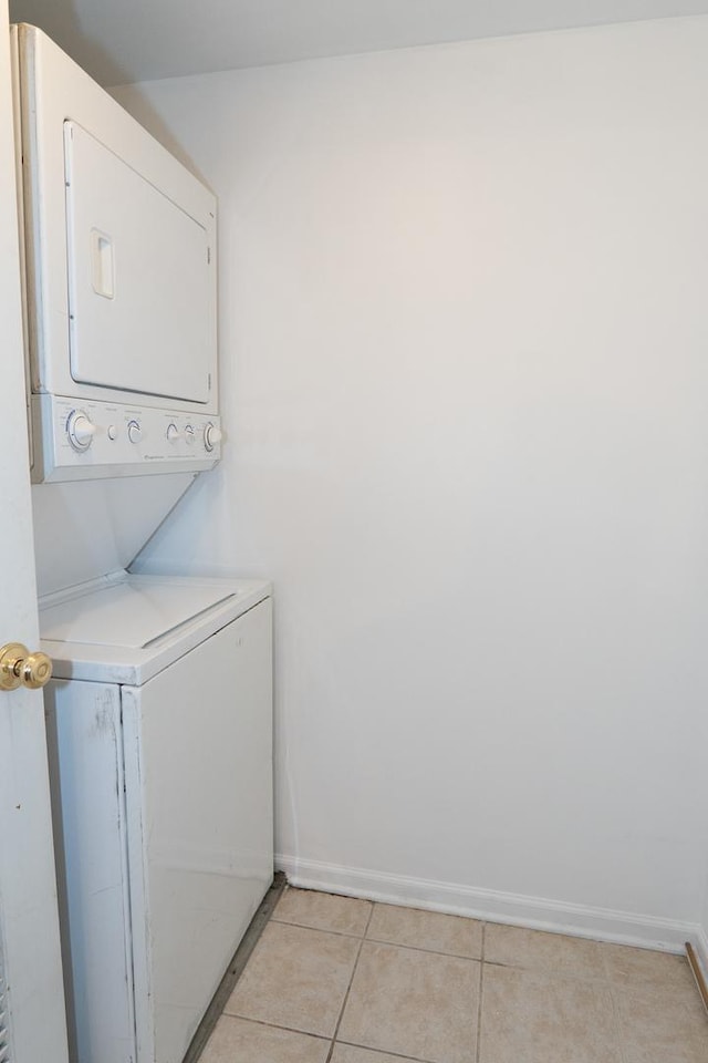 laundry room with stacked washer / dryer, laundry area, baseboards, and light tile patterned floors